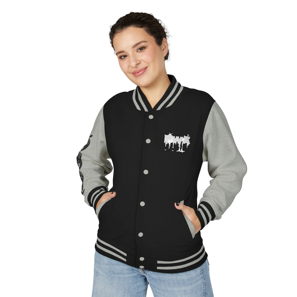 Front view of a woman wearing a black and gray Faith In Motion Varsity Jacket with a white paint-drip graphic.