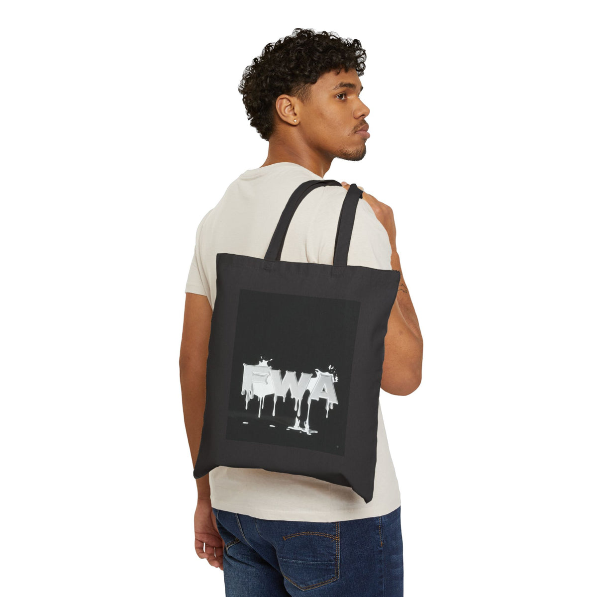 Man wearing a black Drip Paint 'EWA' Canvas Tote Bag with white dripping letters, back view.