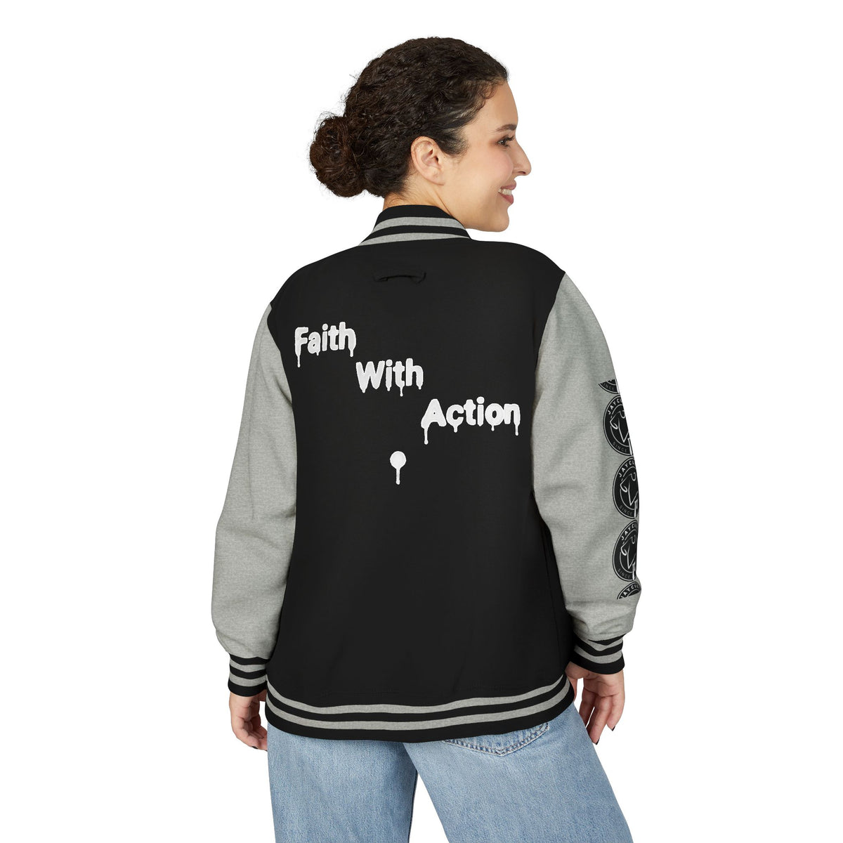 Back view of a woman wearing a black and gray Faith In Motion Varsity Jacket with "Faith With Action" text.